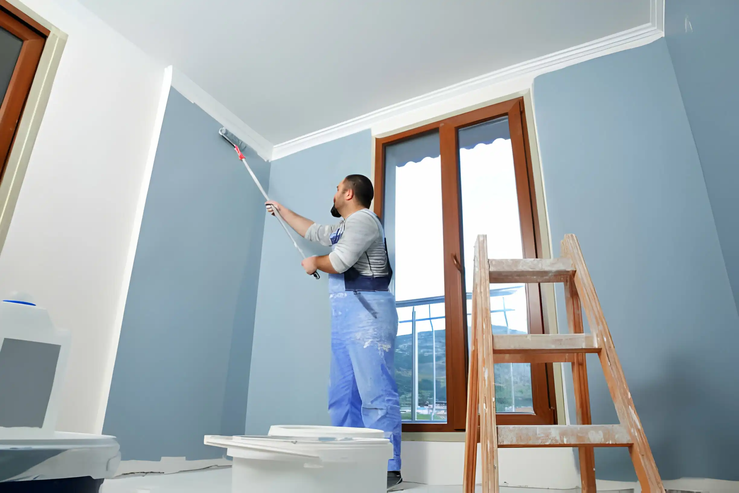Professional painter using a roller to paint blue walls for Gogt Technical Services Dubai.